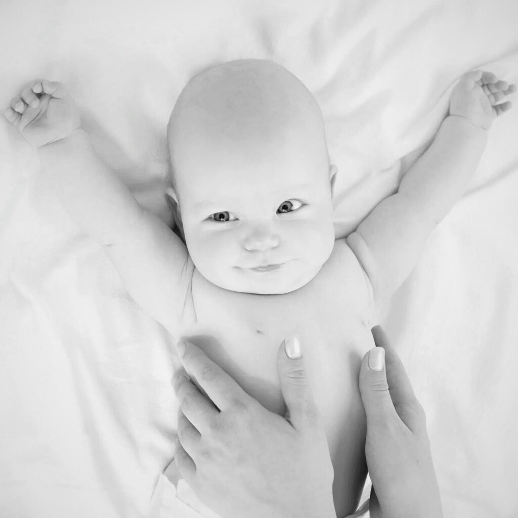 mani che fanno massaggio a un neonato in bianco e nero