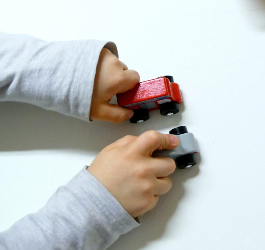 mani di bambino che giocano co macchine